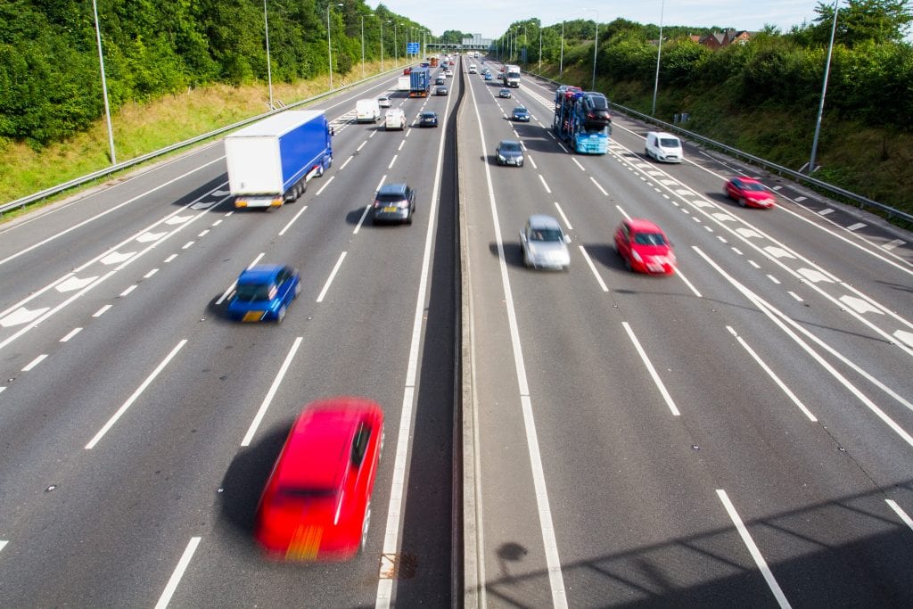 Looking down from above onto the busy carriageways of a motorway or highway that is full of speeding cars and trucks. cars speeding