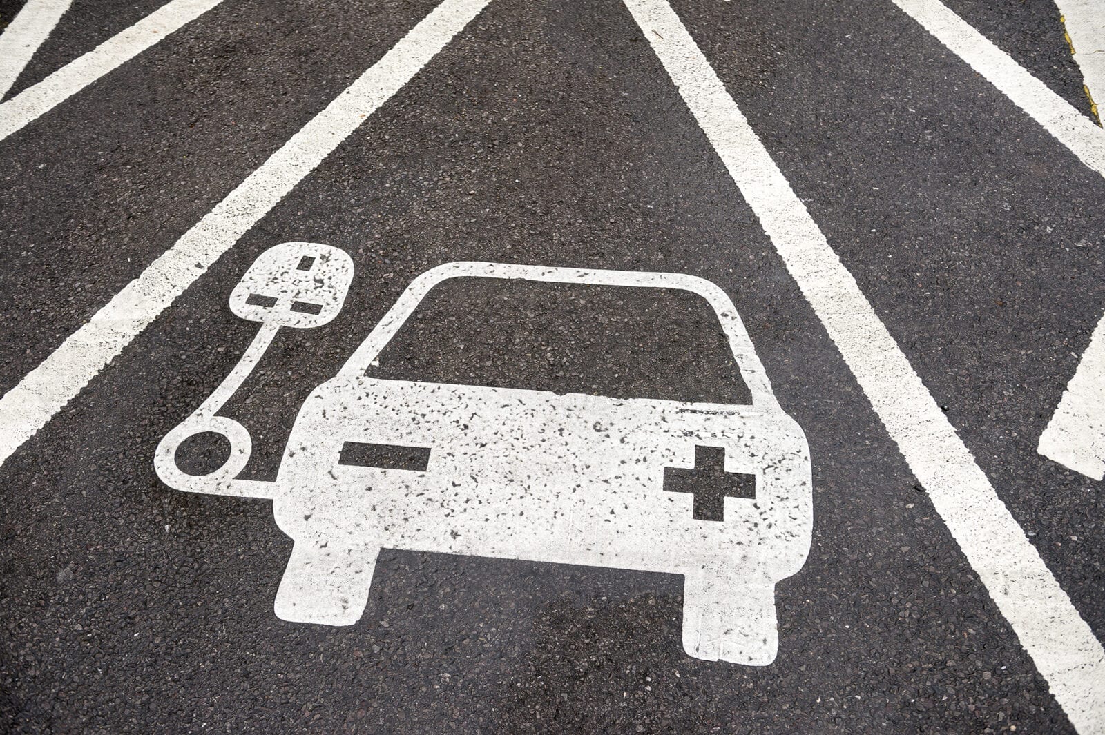 Electric vehicle charging station sign in a parking bay painted increased electric carspots