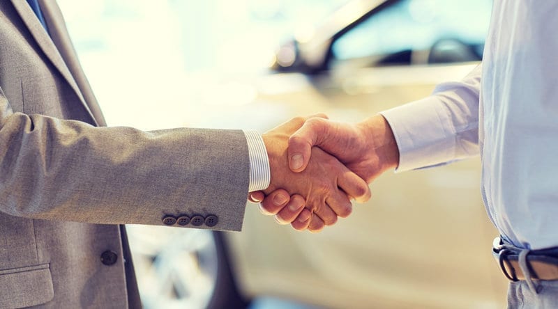 close up of male handshake in auto show or salon dealer website